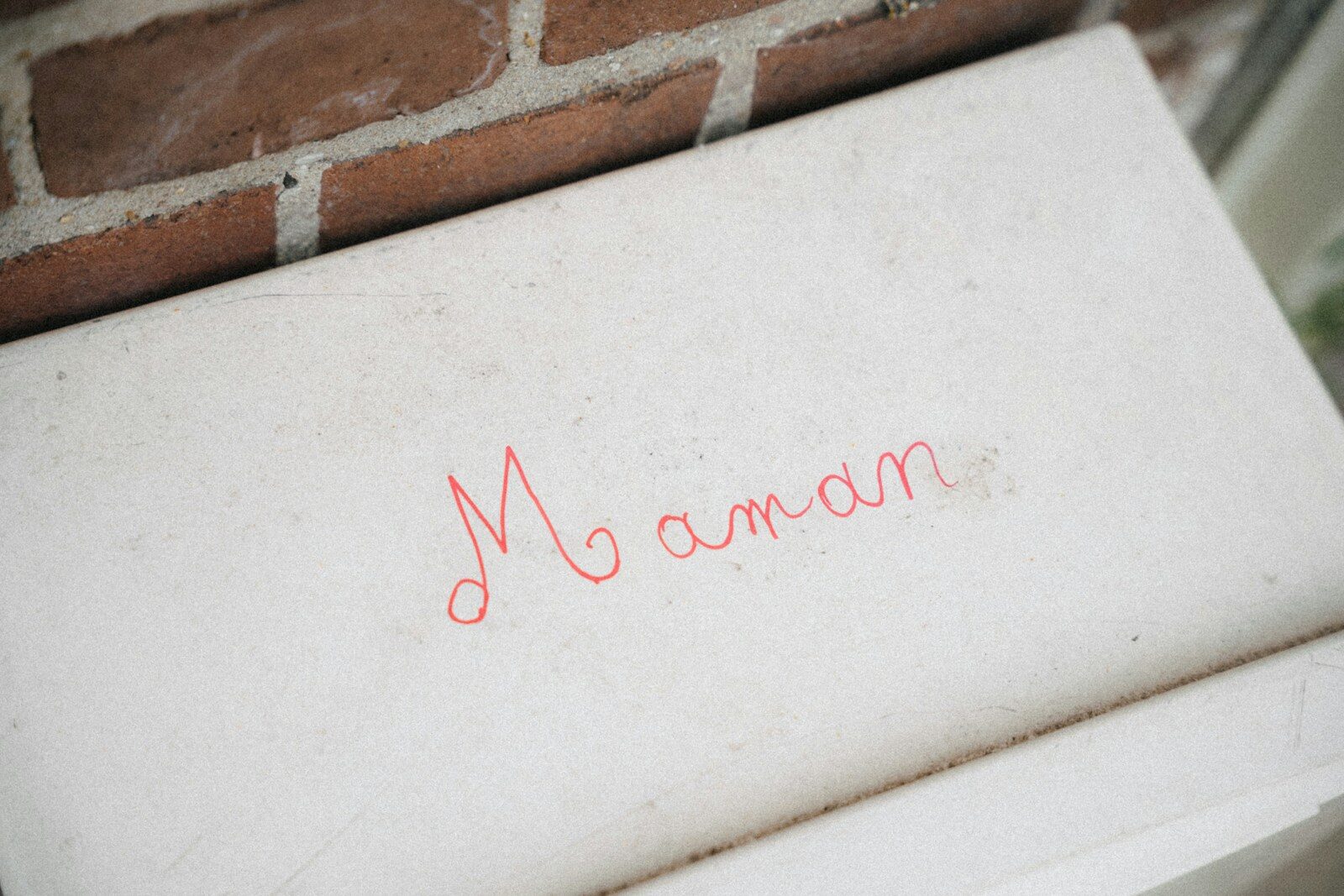 The word maman written in red on a white surface.