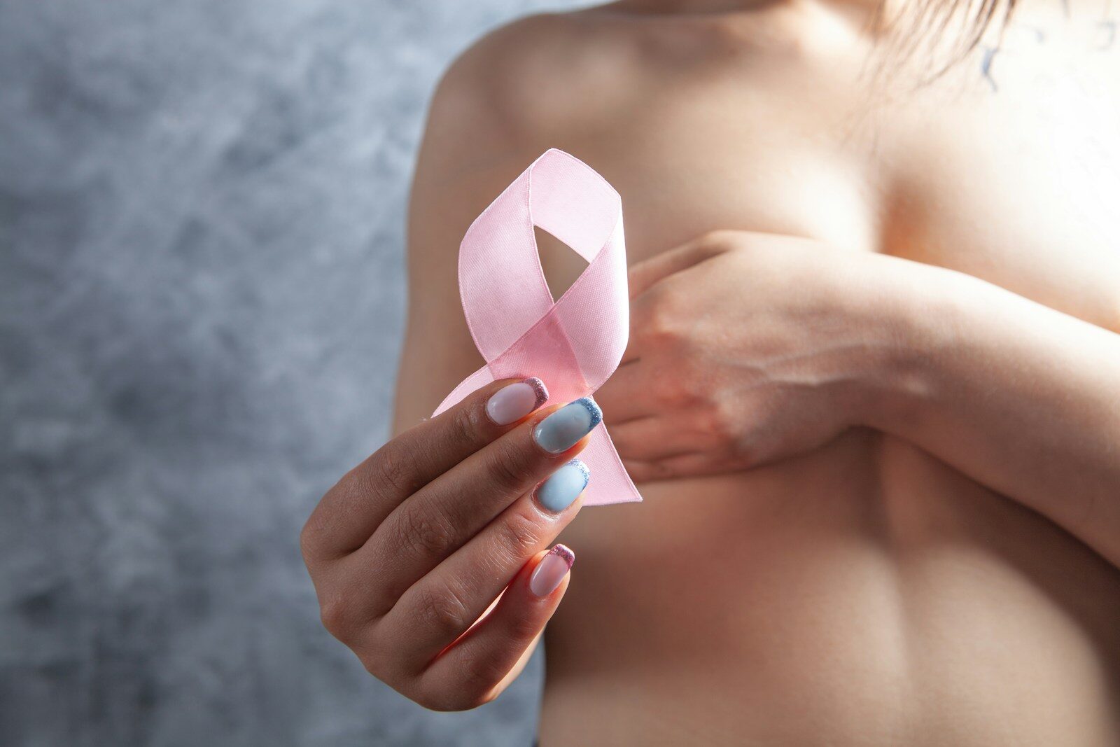 Woman holds pink ribbon for breast cancer awareness